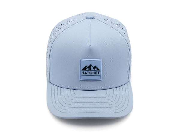 Glacier colored Rover premium performance fitted hat from Hatchet Headwear pictured with a white foreground and background. Hat features a color matched Glacier rubber logo patch with the Hatchet Headwear logo (mountains, tent, and hatchet above the word "HATCHET) in slate blue. The hat is pictured from the front and facing directly at the camera. Camera position is elevated and front facing image of the hat is captured from above.