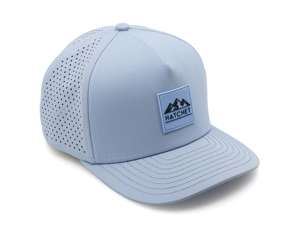 Glacier colored Rover premium performance fitted hat from Hatchet Headwear pictured with a white foreground and background. Hat features a color matched Glacier rubber logo patch with the Hatchet Headwear logo (mountains, tent, and hatchet above the word "HATCHET) in slate blue. The hat is positioned at an approximately 45 degree angle to showcase the front and right-side profile of the hat. Image perspective of the hat is taken such that the hat is photographed from above.