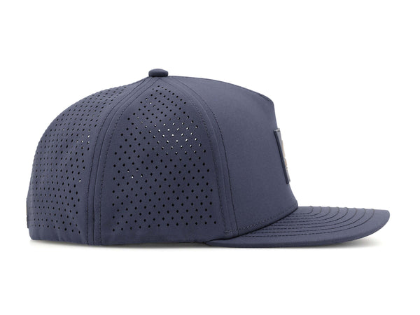Slate Blue colored Rover premium performance fitted hat from Hatchet Headwear pictured with a white foreground and background. The hat is positioned at an approximately 90 degree angle to showcase the right-side profile of the hat. The diamond shaped laser perforations of the hat designed to provide breathability and reduce heat retention are prominently featured.