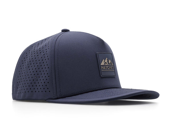 Slate Blue colored Rover premium performance fitted hat from Hatchet Headwear pictured with a white foreground and background. Hat features a color matched Slate Blue rubber logo patch with the Hatchet Headwear logo (mountains, tent, and hatchet above the word "HATCHET) in taupe. The hat is positioned at an approximately 45 degree angle to showcase the front and right-side profile of the hat. Image perspective of the hat is taken such that the hat is slightly above the camera lens position.