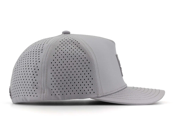 Smoke colored Rover premium performance fitted hat from Hatchet Headwear pictured with a white foreground and background. The hat is positioned at an approximately 90 degree angle to showcase the right-side profile of the hat. The diamond shaped laser perforations of the hat designed to provide breathability and reduce heat retention are prominently featured.
