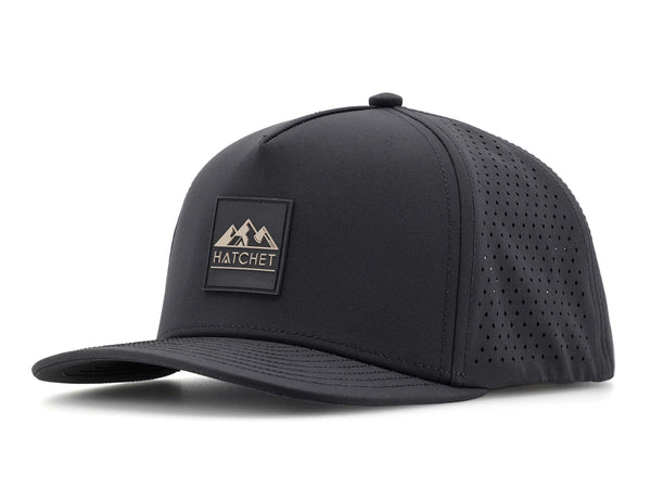 Black colored Rover premium performance fitted hat from Hatchet Headwear pictured with a white foreground and background.  Hat features a color matched Black rubber logo patch with the Hatchet Headwear logo (mountains, tent, and  hatchet above the word "HATCHET) in taupe.  The hat is positioned at an approximately 45 degree angle to showcase the front and left-side profile of the hat.