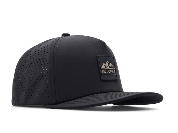 Black colored Rover premium performance fitted hat from Hatchet Headwear pictured with a white foreground and background.  Hat features a color matched Black rubber logo patch with the Hatchet Headwear logo (mountains, tent, and  hatchet above the word "HATCHET) in taupe.  The hat is positioned at an approximately 45 degree angle to showcase the front and right-side profile of the hat.  Image perspective of the hat is taken such that the hat is slightly above the camera lens position.