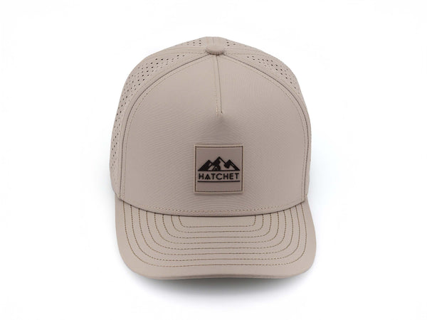 Boulder colored Rover premium performance fitted hat from Hatchet Headwear pictured with a white foreground and background.  Hat features a color matched Boulder rubber logo patch with the Hatchet Headwear logo (mountains, tent, and  hatchet above the word "HATCHET) in Black.  The hat is pictured from the front and facing directly at the camera.  Camera position is elevated and front facing image of the hat is captured from above.