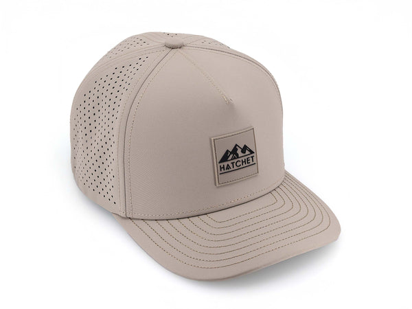 Boulder colored Rover premium performance fitted hat from Hatchet Headwear pictured with a white foreground and background.  Hat features a color matched Boulder rubber logo patch with the Hatchet Headwear logo (mountains, tent, and  hatchet above the word "HATCHET) in black.  The hat is positioned at an approximately 45 degree angle to showcase the front and right-side profile of the hat.  Image perspective of the hat is taken such that the hat is photographed from above.
