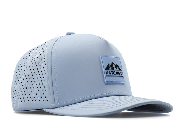 Glacier colored Rover premium performance fitted hat from Hatchet Headwear pictured with a white foreground and background.  Hat features a color matched Glacier rubber logo patch with the Hatchet Headwear logo (mountains, tent, and  hatchet above the word "HATCHET) in slate blue.  The hat is positioned at an approximately 45 degree angle to showcase the front and right-side profile of the hat.  Image perspective of the hat is taken such that the hat is slightly above the camera lens position.