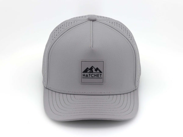 Smoke colored Rover premium performance fitted hat from Hatchet Headwear pictured with a white foreground and background.  Hat features a color matched Smoke rubber logo patch with the Hatchet Headwear logo (mountains, tent, and  hatchet above the word "HATCHET) in black.  The hat is pictured from the front and facing directly at the camera.  Camera position is elevated and front facing image of the hat is captured from above.
