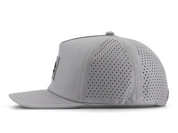 Smoke colored Rover premium performance fitted hat from Hatchet Headwear pictured with a white foreground and background.  The hat is positioned at an approximately 90 degree angle to showcase the left-side profile of the hat.  The diamond shaped laser perforations of the hat designed to provide breathability and reduce heat retention are prominently featured.