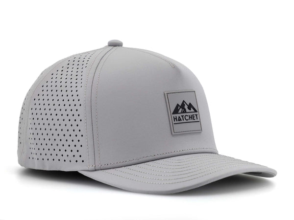 Smoke colored Rover premium performance fitted hat from Hatchet Headwear pictured with a white foreground and background.  Hat features a color matched Smoke rubber logo patch with the Hatchet Headwear logo (mountains, tent, and  hatchet above the word "HATCHET) in black.  The hat is positioned at an approximately 45 degree angle to showcase the front and left-side profile of the hat.
