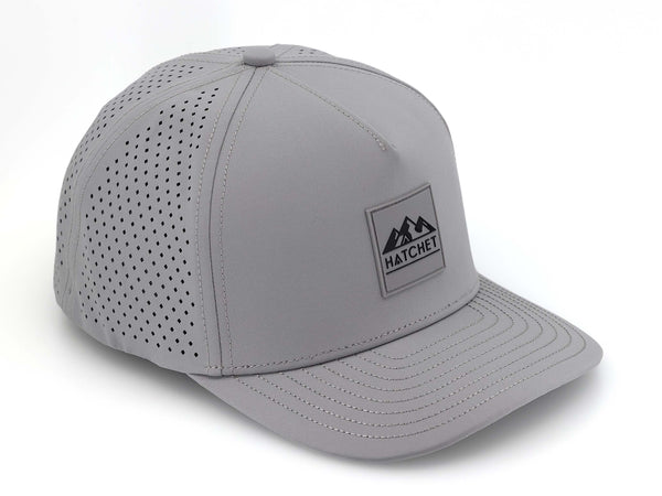 Smoke colored Rover premium performance fitted hat from Hatchet Headwear pictured with a white foreground and background.  Hat features a color matched Smoke rubber logo patch with the Hatchet Headwear logo (mountains, tent, and  hatchet above the word "HATCHET) in black.  The hat is positioned at an approximately 45 degree angle to showcase the front and right-side profile of the hat.  Image perspective of the hat is taken such that the hat is photographed from above.